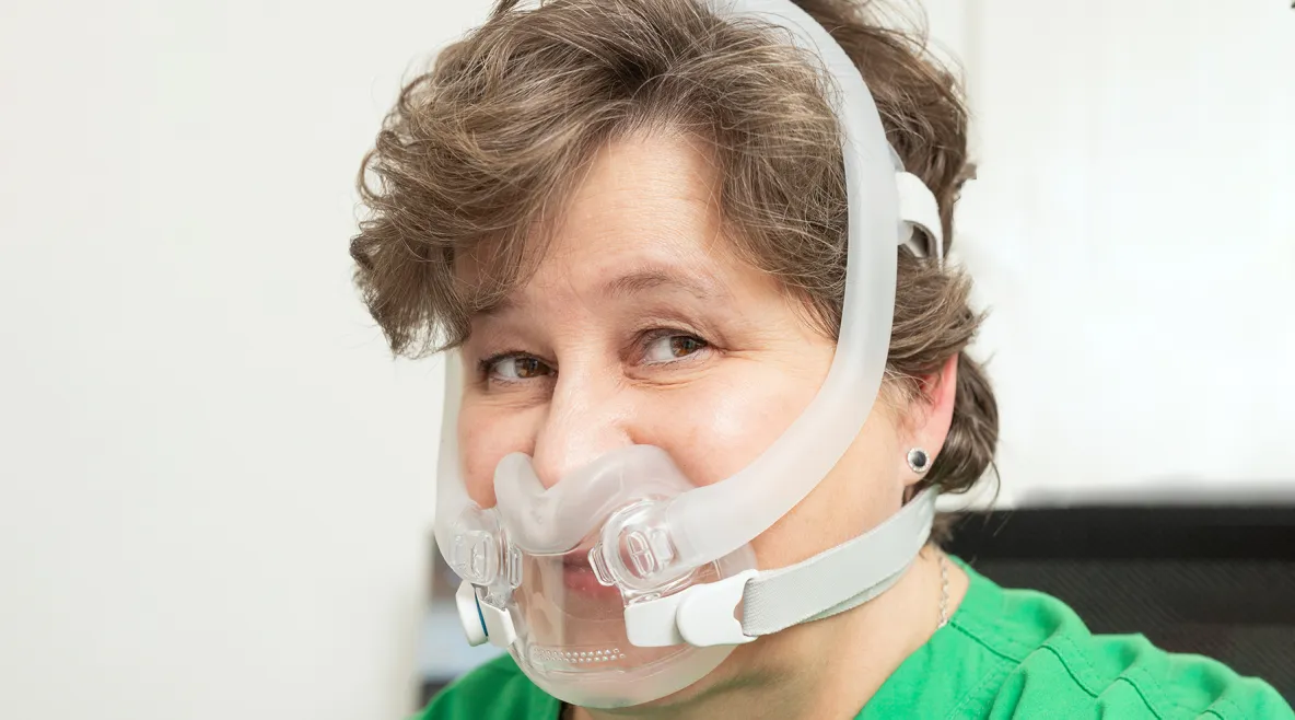 Nainen, jolla on CPAP-maski kasvoillaan. 