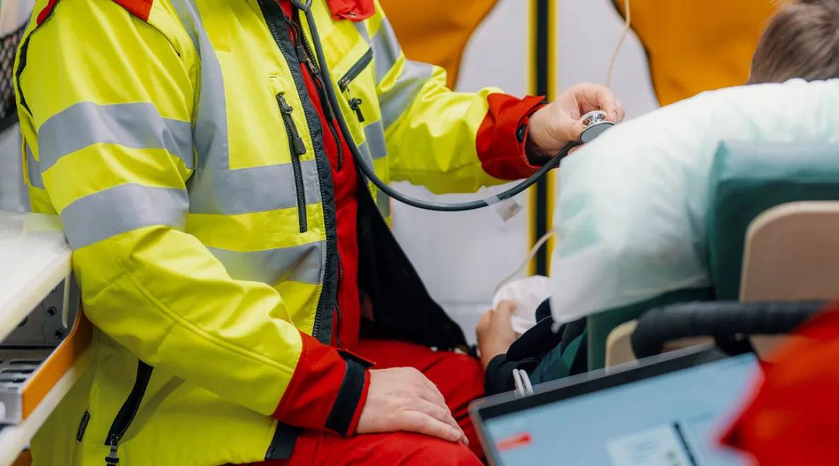 Ensihoitaja tarkkailee potilasta ambulanssissa.