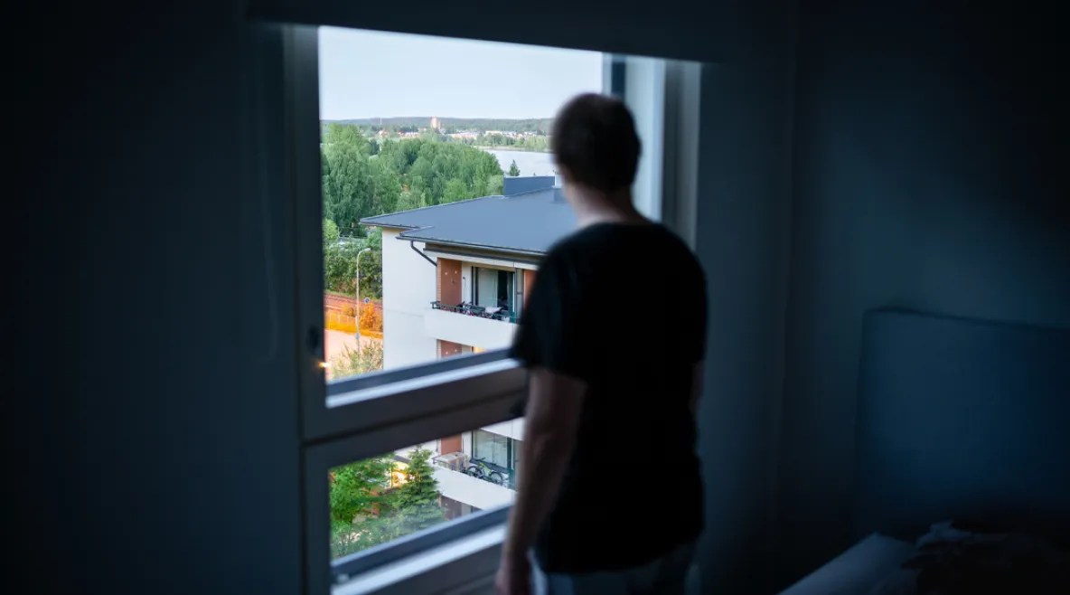 Työttömyys heikentää merkittävästi etenkin työikäisten miesten mielenterveyttä. Ihmishahmo seisoo ikkunan edessä selin kameraan tummassa huoneessa.