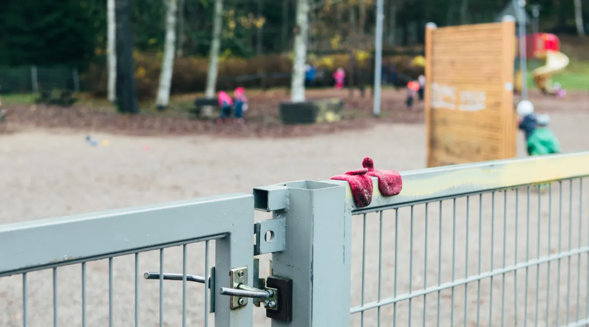 Syksyinen päiväkodin piha ja portti ja aita.