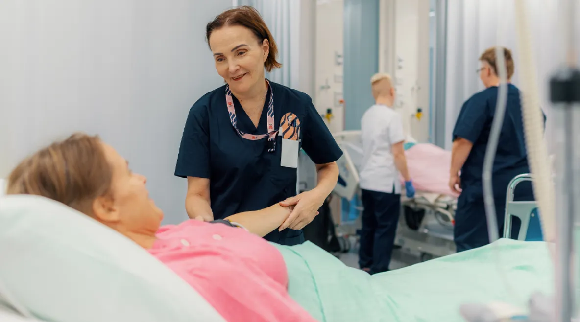 Keski-ikäinen hoitaja työssään sairaalassa auttaa potilasta – hyvät työolot ja terveystottumukset tukevat ikääntyvien työntekijöiden työkykyä ja jaksamista.