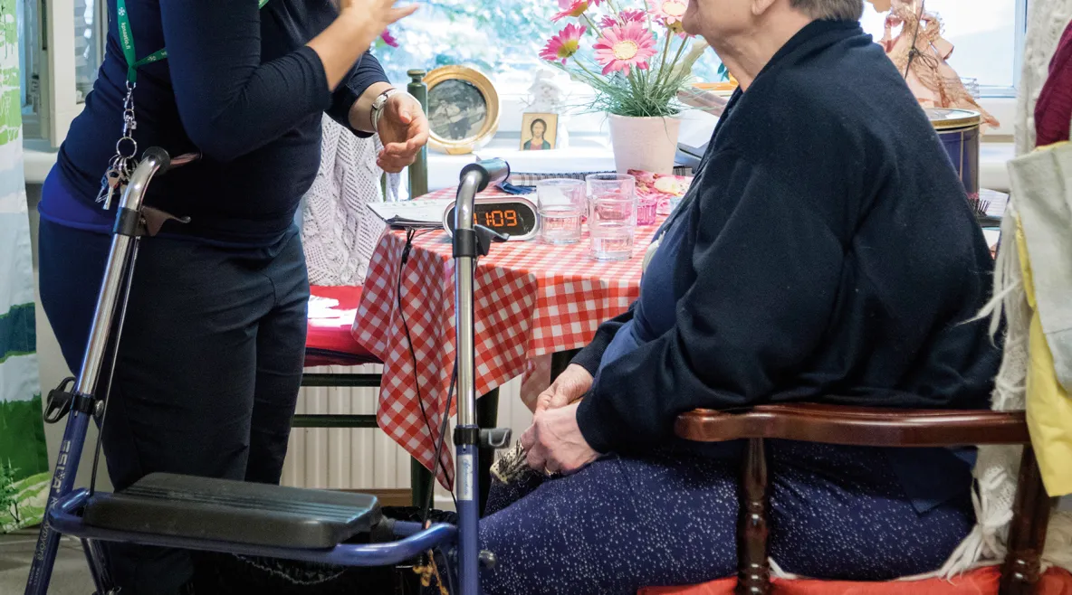 istuva vanhus ja hoitaja tämän puoleen kääntyneenä.