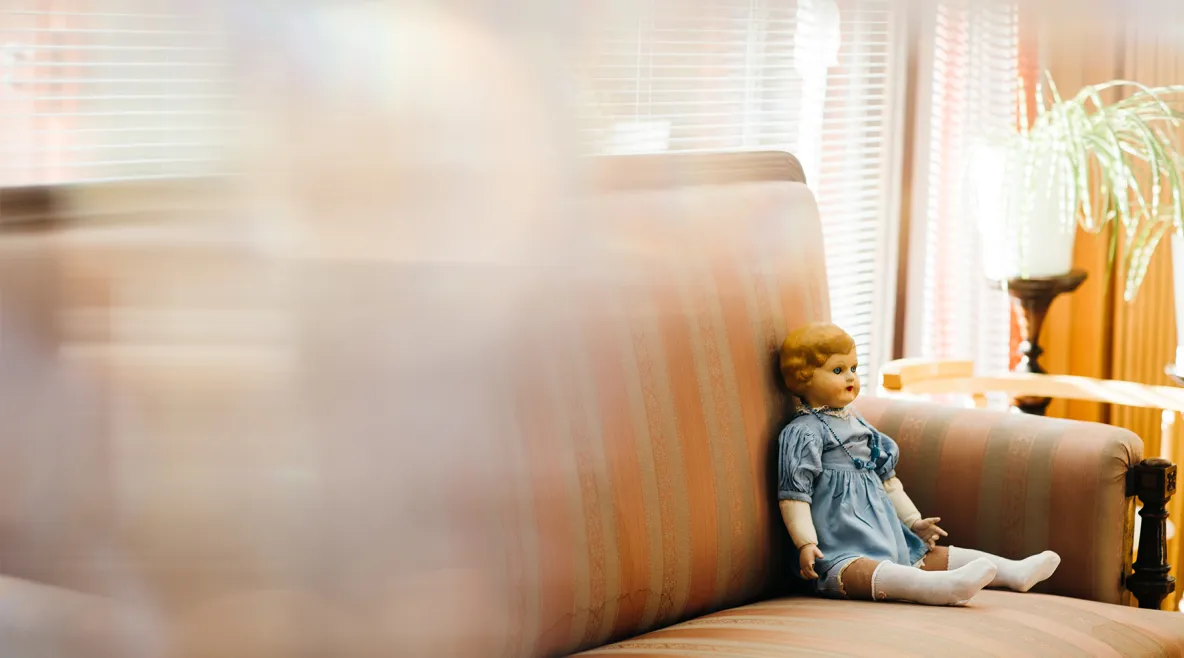 tyttönukke istuu sohvan kulmassa