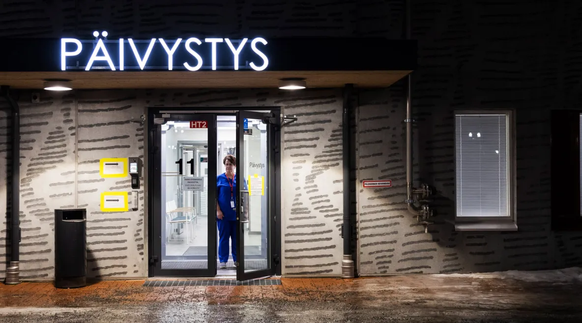 Varkauden perusterveydenhuollon yöpäivystys kuvattuna yöllä. Hoitaja seisoo ovella.
