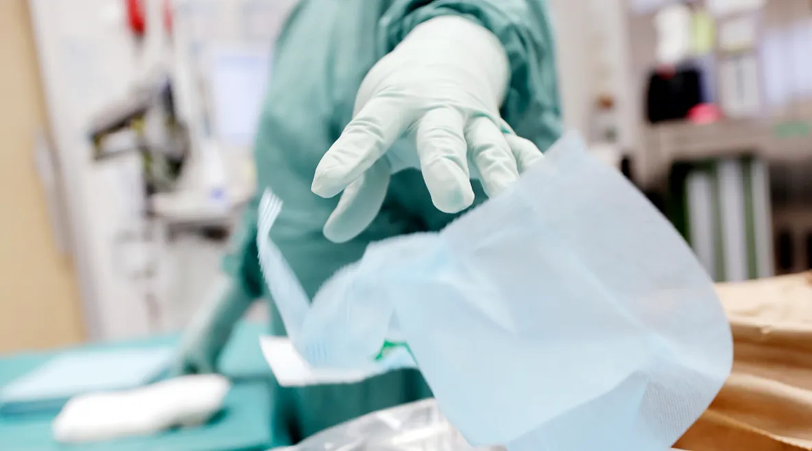 Käsi, jossa hansikas heittää roskan roskikseen.