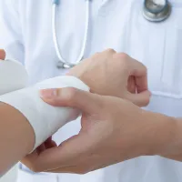 Lääkäri käärii sideharson potilaan käden ympärille.