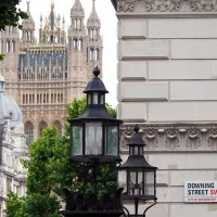 Etualalla kyltti, jossa lukee Downing Street ja taustalla parlamenttitalo