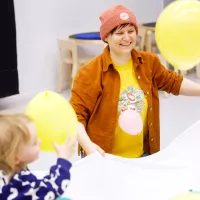 Opiskelija Rita Häkkinen leikkii lasten ja äitien kanssa perhekahvilassa.