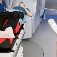 Kaksi röntgenhoitajaa laittaa potilasta röntgenlaitteeseen
