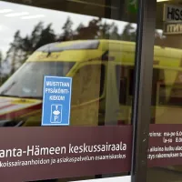 Ambulanssin kuva heijastuu Kanta-Hämeen keskussairaalan lasiovista.