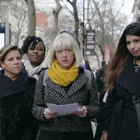 Lasikatto-dokumentin mainoskuvassa kuusi naista seisoo kadulla. Keskimmäisellä on kädessään papereita.