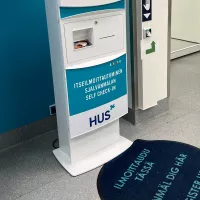 Husin ilmoittautumisautomaatti käytävällä.