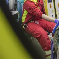 Anonyymi ensihoitaja hoitaa potilasta ambulanssissa.