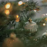 Kuvassa on valaistu joulukuusi, jonka oksasta roikkuu joulukoriste.