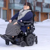 Aino Ikävalko pyörätuolissa kotinsa edustalla.