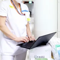 Sairaanhoitaja kirjaa kannettavalle tietokoneelle.