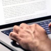 Henkilö kirjoittamassa blogitekstiä kannettavalla tietokoneella.