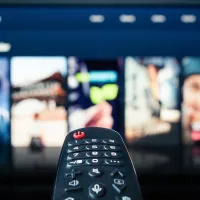 Kaukosäädin osoittaa televisioruudulla näkyvää suoratoistopalvelua.