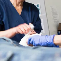 Kaksi hoitajaa potilaan äärellä. 