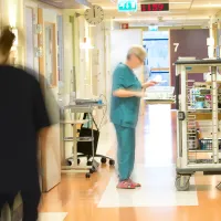 Hoitaja osaston käytävällä jakamassa ruoka-annoksia.