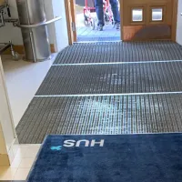 Sisäänkäynti, jossa kuramatossa teksti &quot;HUS&quot;
