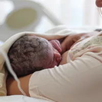 Äiti imettää vastasyntynyttä vauvaa sairaalassa.