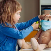 Pikkutyttö leikkii lääkäriä ja antaa rokotteen pehmolelu jänikselle.