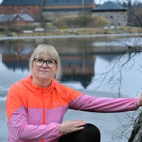 Marika Orava ulkoiluvaatteissa, taustalla Hämeen linna.