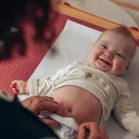 Vauva hymyilee hoitopöydällä.