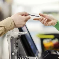 Kassanhoitaja ottaa luottokortin ja veloittaa päivittäistavaroita supermarketissa.