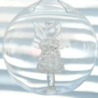 Kuvassa on lasinen enkeli-koriste lasipallossa.