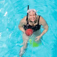 Emmi Kuorttinen uima-altaassa pallon kanssa.