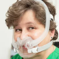 Nainen, jolla on CPAP-maski kasvoillaan. 