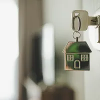 Ovessa on lukko ja siinä avain, jossa roikkuu talonmuotoinen avaimenperä