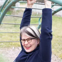 Väitöskirjatutkija Johanna Olli roikkuu lasten kiipeilytelineessä.