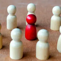 Punainen hahmo, jota ympäröivät beige-hahmot, jotka edustavat vaikutusvaltaa, joka voi viitata johtajuuteen tai häirintään. Tehy-lehti tekee juttua työpaikkakiusaamisesta.