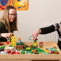 Päiväkodin aluejohtaja Ida Åsvik ja lastenhoitaja Gabriella Ljunggren ovat töissä Pedersöressä, jonka varhaiskasvatuksessa halutaan keskittyä hyvään. He istuvat puisen pöydän ympärillä, jossa on lasten dublo-palikoita.