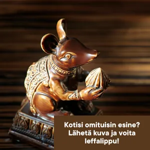 Pronssinen koriste-esine, joka esittää istuvaa, koristeellisiin vaatteisiin puettua hiirtä tai rottaa. Eläin pitelee käsissään simpukan muotoista esinettä ja istuu koristeellisella jalustalla. Taustalla puunsyinen pinta.