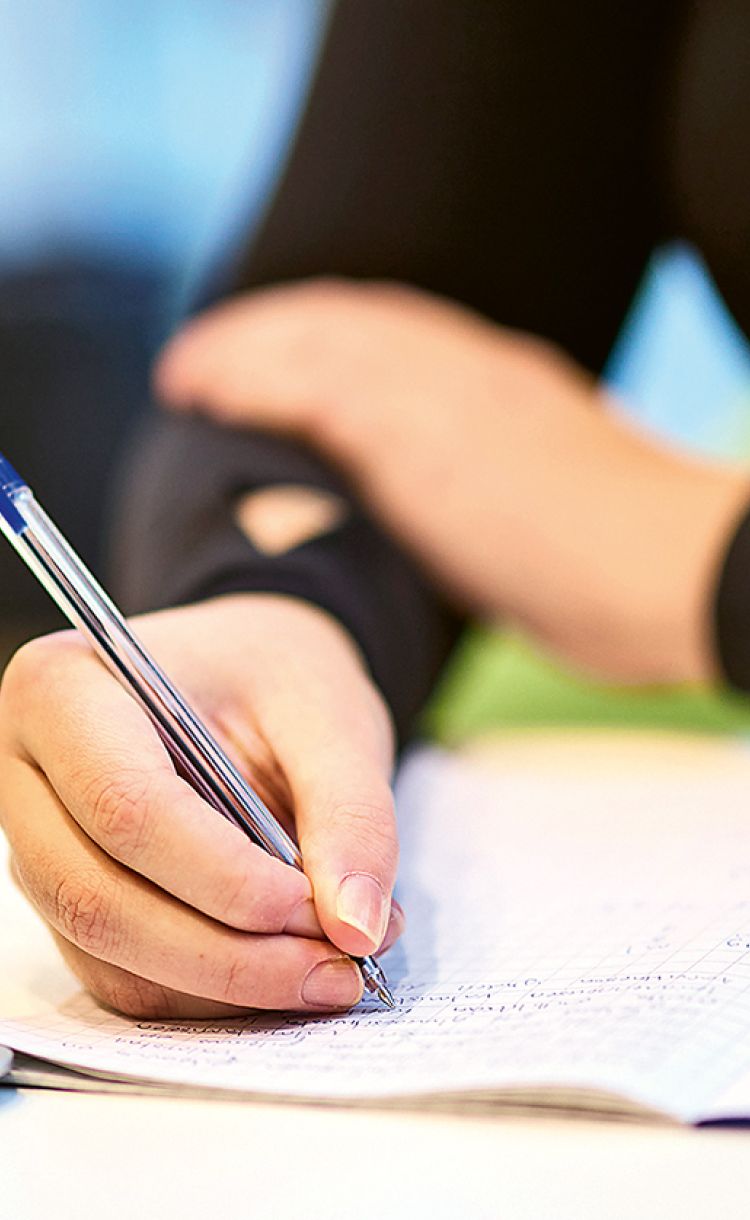 Cecilia Suomi laskemassa lääkelaskuja. Lähikuva käsistä ja laskuvihkosta.