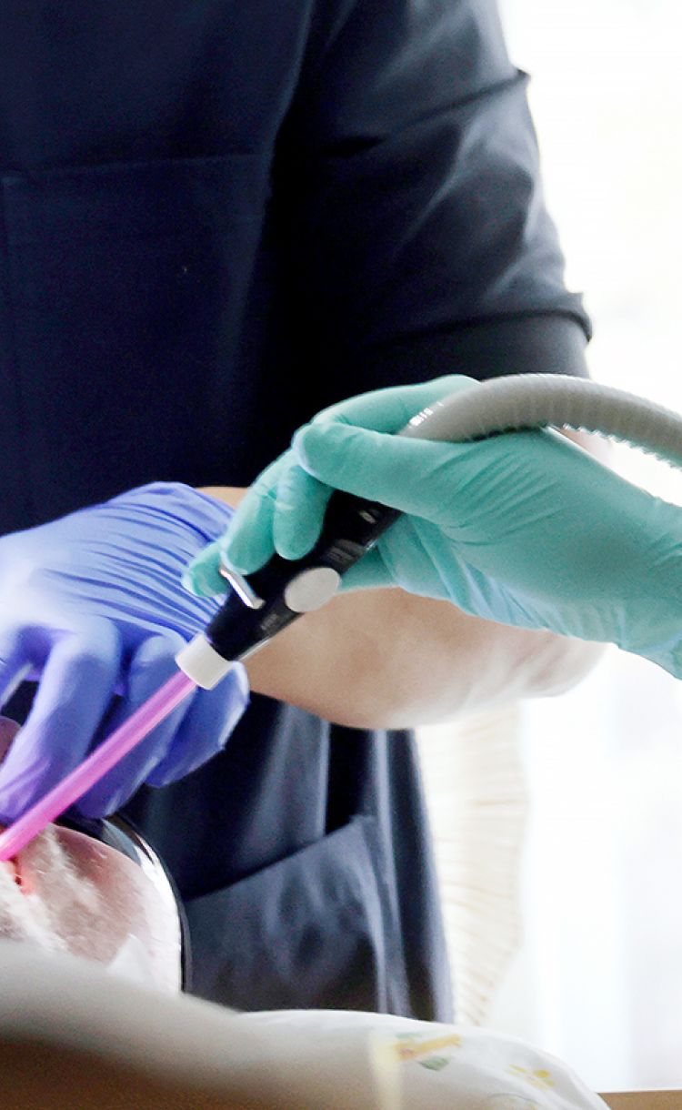 Hammashoitaja avustaa hammaslääkäriä. Potilas kuvassa suu auki.