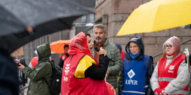 Sairaanhoitaja Nizo Dara puhumassa Eduskuntatalon rapuilla kaatosateessa.