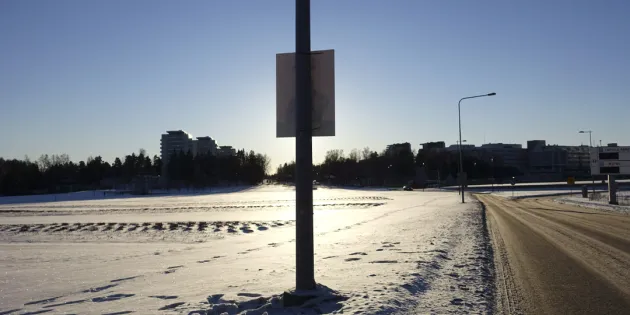 Aluevaalimainos tien poskessa aurinkoisessa säässä.