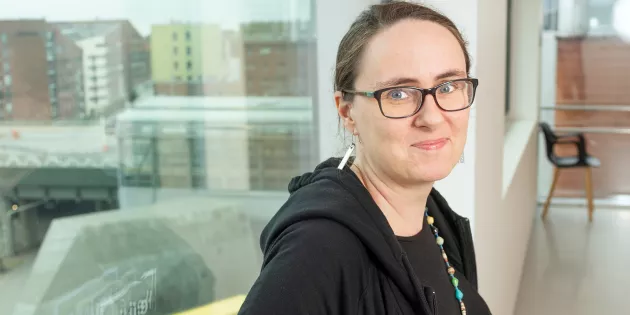 Karoliina Himanen ikkunan ääressä. Ikkunasta avautuu maisema Kalasatamaan. 