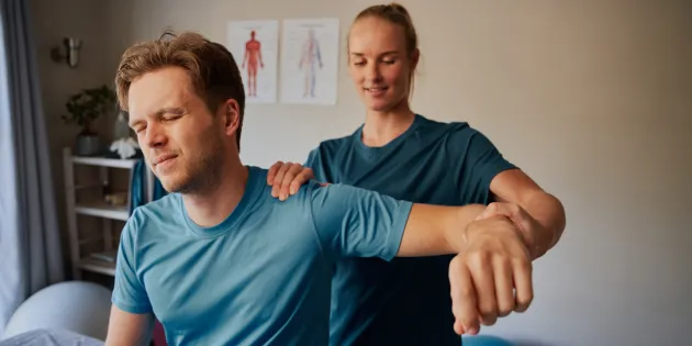 Fysioterapeutti venyttää ja tutkii potilaan käsivartta vastaanotolla.
