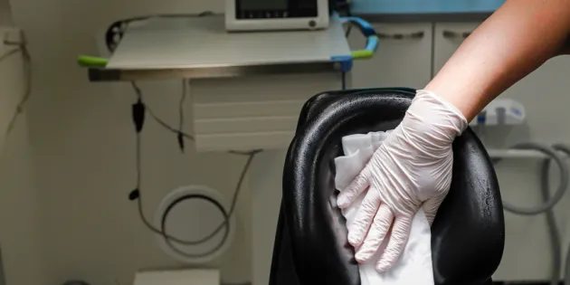 Suuhygienisti puhdistamassa puhdistusliinalla hammashoitotuolia.