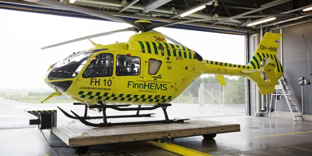FinnHEMS helikopteri siiretään ulos hallista liikkuvalla lavetilla. 