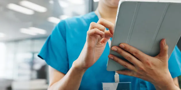 Hoitaja katsoo keskittyneesti tabletilta tietoja.