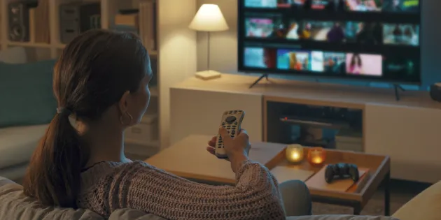 Millaisena hoitotyön ammattilainen näkyy elokuvissa – sankarina, sivuhahmona vai stereotyyppinä? Nainen katsoo elokuvavalikoimaa tv:n suoratoistopalvelusta.