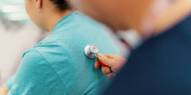 Hoitaja kuuntelee potilaan hengitysääniä stetoskoopilla.