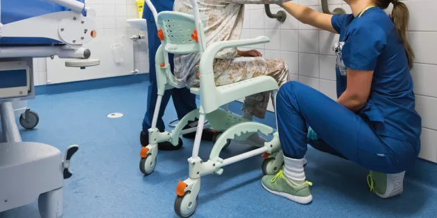 Sairaanhoitaja ja lähihoitaja pesemässä vanhusta.